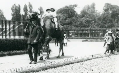 Deux jeunes visiteurs chevauchant un chameau de Bactriane, conduit par un gardien, au Zoo de Londres, août 1922